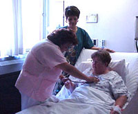 Paziente in un letto d'ospedale accudita da due infermiere