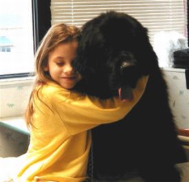 Una bambina abbraccia un grande cane nero