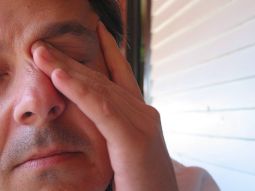 Uomo con gli occhi chiusi e una mano sull'occhio sinistro: simboleggia la sindrome da fatica cronica