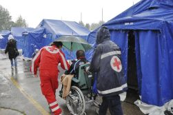 Persona con disabilità e due volontari della Croce Rossa in una tendopoli in Emilia