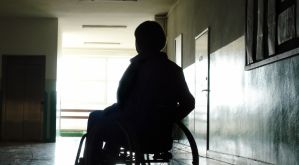Ombra di giovane con disabilità (di spalle) all'interno di un edificio