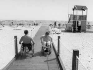 Due persone in carrozzina in spiaggia