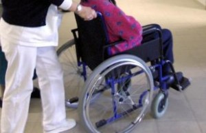 Particolare di operatrice sanitaria che spinge una donna con disabilità in carrozzina