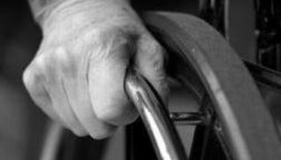 Mano di persona con disabilità stretta sulla ruota della sua carrozzina