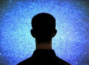Uomo fotografato di spalle di fronte a una specie di video su sfondo blu e bianco