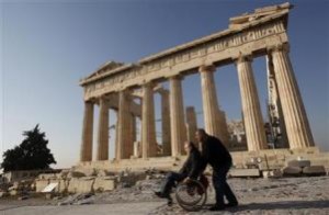A man pushes a disabled man on a wheelchair in front of the Parthenon temple during a protest atop the Acropolis hill in Athens