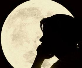 Profilo di donna al buio. Sullo sfondo la luna piena
