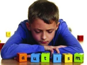 Ragazzo con dei cubi colorati davanti, che compongono la parola "Autism"