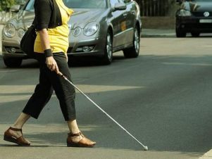 Particolare di donna cieca con il bastone bianco che attraversa una strada