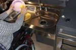 Una persona in carrozzina che lava le stoviglie nella cucina "Ergokitchen"