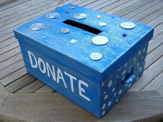 Urna azzurra con la scritta "DONATE" e alcune monete sopra ad essa