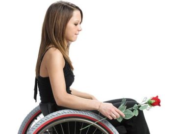 Giovane donna in carrozzina fotografata di profilo, con una rosa in mano