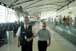 Un giovane con disabilità visiva accompagnato da un assistente all'interno di un aeroporto