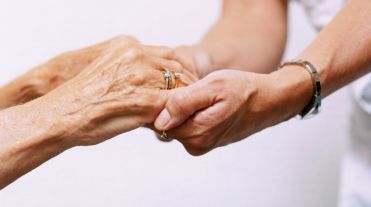 Mani di donna che stringono mani di donna anziana