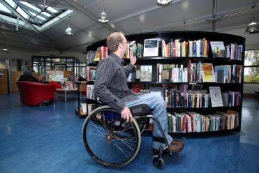 Persona in carrozzina in una biblioteca accessibile