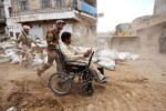 Un giovane yemenita in carrozzina, spinto da un altrettanto giovane soldato, in una zona del Paese della Penisola Arabica ove da tempo si vive in uno stato di guerra