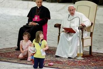 Papa Francesco parla, mentre due bimbe con sindrome di Down giocano davanti a lui