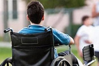 Ragazzo con disabilità in carrozzina, fotografato di spalle