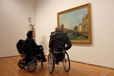 Persone con disabilità motoria in carrozzina in visita a un museo