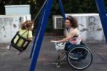 Una madre con disabilità motoria fa giocare la propria bimba sull'altalena