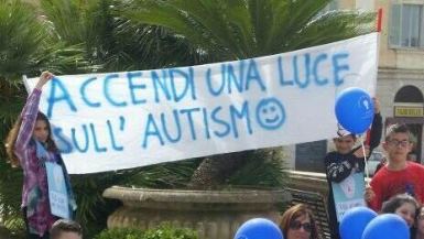Bambini con lo striscione recante "Accendi una luce sull'autismo", slogan dell'ANGSA di Sassari