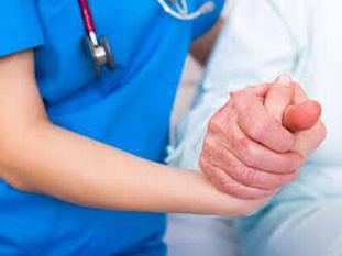 Mano di operatore sanitario che stringe la mano di una persona con la malattia di Parkinson