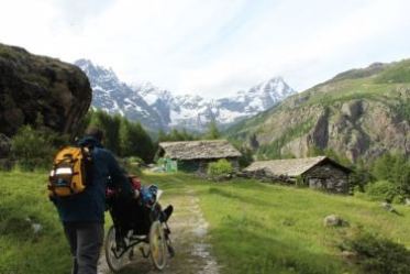 Persona con disabilità su un sentiero di montagna, insieme al suo accompagnatore