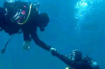 Un sub dà la mano a un altro sott'acqua