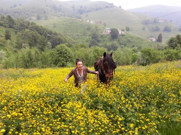 Michela Locatelli in un campo di fiori gialli insieme a un cavallo