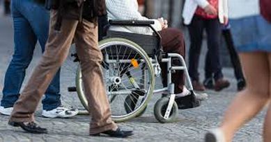 Particolare di gambe di persone e di carrozzina con persona con disabilità