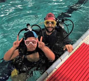 Giovane persona con disabilità in piscina, insieme a un istruttore di HSA Italia