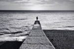 Persona sola davanti al mare, in fondo a unqa passerella
