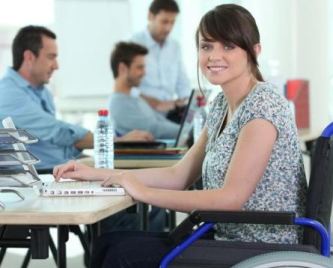 Giovane donna con disabilità in carrozzina al lavoro al computer