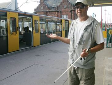 Persona con disabilità visiva che sta per prendere un treno