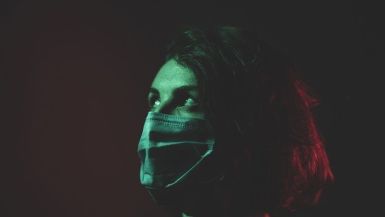 Donna con la mascherina in una stanza buia