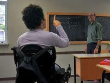 Alunno con disabilità che alza un dito davanti a un docente