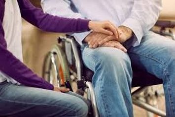 Mano di caregiver su mano di persona con disabilità