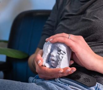 Madre con disabilità visiva tiene in mano una "scultura" in 3D della sua ecografia prenatale