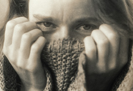 Viso di donna forografato in bianco e nero, con la parte inferiore della faccia coperta da un maglione