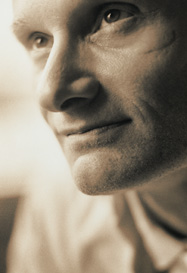 Uomo fotografato in bianco e nero, con espressione tra il soddisfatto e il perplesso