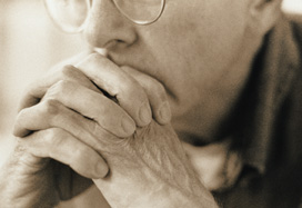 Particolare del volto di un uomo anziano - fotografato in bianco e nero - con espressione perplessa e mani sulla bocca