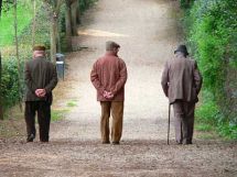 Tre uomini anziani, fotografati di spalle, in una casa di riposo