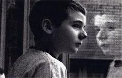 Foto in bianco e nero di bimbo che si guarda allo specchio e della sua immagine riflessa