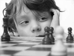 Bambino gioca a scacchi con espressione perplessa