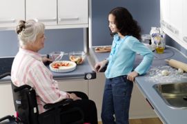 Donna con disabilità in cucina, insieme a un'assistente