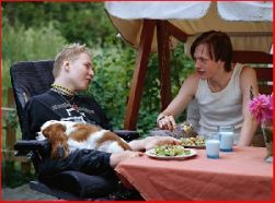 Due ragazzi, di cui uno tiene in braccio un cane, seduti a tavola