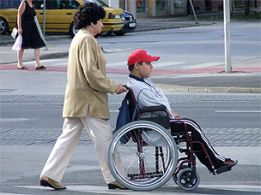 Ragazzo con disabilità in carrozzina, accompagnato dalla madre