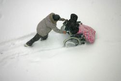 Persona in carrozzina spinta sulla neve