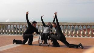 Linda Galeotti esegue una figura di danza assieme a due ballerini, su una terrazza a mare