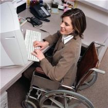 Giovane donna in carrozzina al lavoro al computer